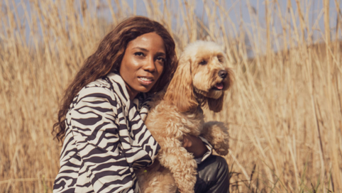 Woman with a dog sitting in a field during a UK road trip adventure